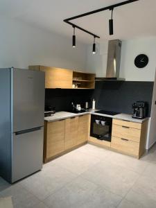 a kitchen with a stainless steel refrigerator and wooden cabinets at Apartament w Dolinie Sanu 1 in Lesko