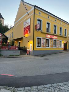 ein gelbes Gebäude an der Straßenseite in der Unterkunft Pension Stadt Grein in Grein