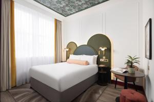 Un dormitorio con una gran cama blanca y una mesa en Holiday Inn London Oxford Circus, an IHG Hotel en Londres