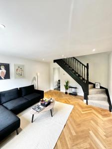 a living room with a black couch and a staircase at Canal Mews in Manchester