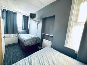a small bedroom with two beds and a tv at Lynalan Hotel in Blackpool