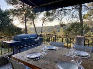 einen Holztisch mit Tellern und Weingläsern auf dem Grill in der Unterkunft Villa au calme dans un domaine boisé in La Motte