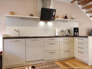a kitchen with white cabinets and a black counter top at Dünenrose in Spiekeroog