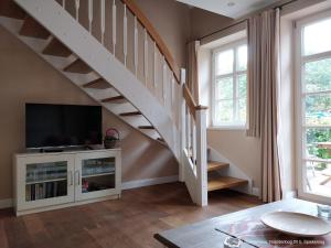 a living room with a staircase with a flat screen tv at Dünenrose in Spiekeroog