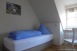 a bed with blue pillows on it in a room at Dünenrose in Spiekeroog