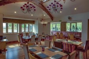 uma sala de jantar com mesas, cadeiras e janelas em The Manor Boutique Hotel Restaurant and Bar em Conwy