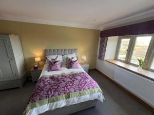 um quarto com uma cama com lençóis e almofadas roxos em The Manor Boutique Hotel Restaurant and Bar em Conwy