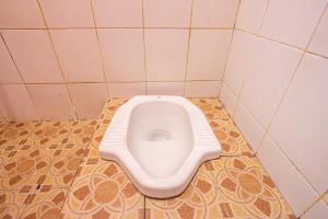 a toilet in a bathroom with a tiled floor at OYO Life 93405 Montong Are Residence in Tjakranegara