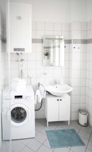 a white bathroom with a washing machine and a sink at Das Quartier in Klagenfurt