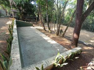 einen Betonsteg in einem Park mit Bäumen in der Unterkunft Casa da Floresta in Lavras