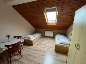 een kamer met 2 bedden, een tafel en een raam bij Penzión D+D in Zázrivá