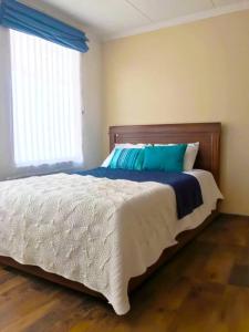 a bedroom with a large bed with a blue pillow at Vive con nosotros tusvacaciones in Cuenca