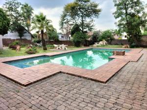 a swimming pool with two dogs in a yard at GELET GUESTHOUSE in Roodepoort