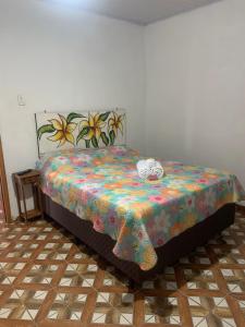 a bedroom with a bed with a floral bedspread and stuffed animals on it at Pouso nossa senhora das merces in Tiradentes