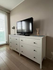uma cómoda branca com uma televisão por cima em Ola Apartment em Gdansk