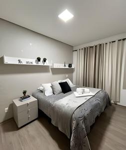 a white bedroom with a large bed and a white cabinet at Apto Apaixonante com Piscina Aquecida 4min centro in Gramado