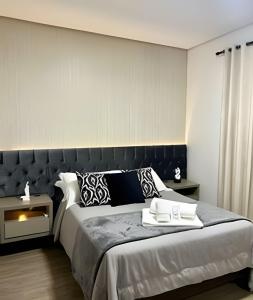 a bedroom with a large bed with a black headboard at Apto Apaixonante com Piscina Aquecida 4min centro in Gramado