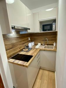 a kitchen with a sink and a microwave at Héli apartman in Hajdúszoboszló