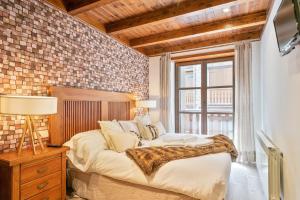 1 dormitorio con 1 cama grande y pared de ladrillo en Luderna - Apartamento Val de Ruda B1 Morèdo, en Baqueira Beret