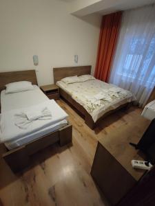 2 camas individuales en una habitación con ventana en Pensiunea Paradis Baile Herculane, en Băile Herculane
