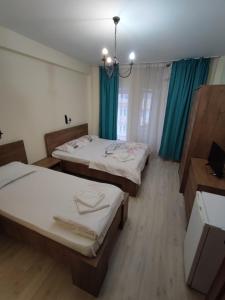 2 Betten in einem Zimmer mit blauen Vorhängen in der Unterkunft Pensiunea Paradis Baile Herculane in Băile Herculane