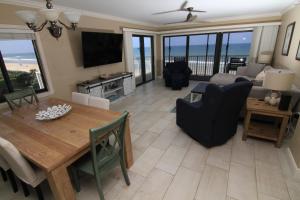 ein Wohnzimmer mit einem Tisch, Stühlen und einem TV in der Unterkunft Direct oceanfront with stunning corner views and pool access! in New Smyrna Beach