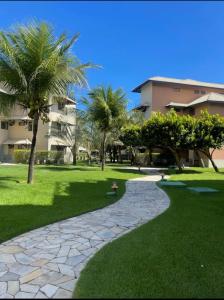 a walkway in a park with palm trees and a building at Beach Place Resort - Térreo in Aquiraz