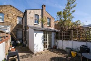 a brick house with a white door and a fence at Cozy House with Character & Garden. in London