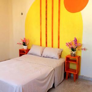 1 dormitorio con 1 cama y 2 mesas con flores en Casa Aeropuerto Mérida, Yucatán, en Mérida