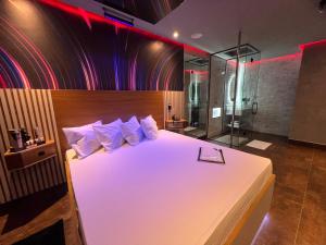 um quarto com uma grande cama branca e um chuveiro em Motel Prestige Pinda em Pindamonhangaba
