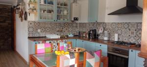 a kitchen with blue cabinets and a table with a bowl of fruit at Casa dos Bardos in Alvações do Corgo