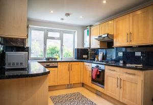 a kitchen with wooden cabinets and black counter tops at Cozy 3 Bedroom house in Finchley in Totteridge