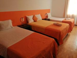 2 camas en una habitación con paredes de color naranja en Hotel Conquistadores Inn, en Ica