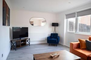a living room with a television and a blue chair at Cozy 3 Bedroom house in Finchley in Totteridge