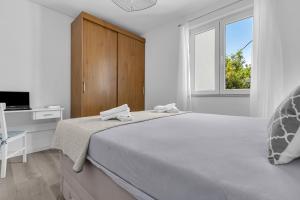 Un dormitorio blanco con una cama grande y una ventana en Apartman Bokšić 2, en Makarska