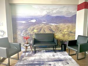 a waiting room with two chairs and a painting of a mountain at Mahle Comfort Hotel in Campina Grande do Sul