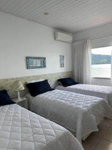 a bedroom with two beds and a window at Casa de veraneio com deck em Passa Terra, Ilha Grande in Angra dos Reis