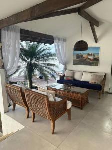 a living room with chairs and a couch and a palm tree at Casa de veraneio com deck em Passa Terra, Ilha Grande in Angra dos Reis