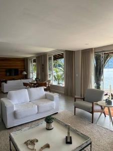 a living room with a white couch and a table at Casa de veraneio com deck em Passa Terra, Ilha Grande in Angra dos Reis