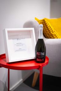 una botella de vino en una mesa roja con una caja en Das Quartier, en Klagenfurt