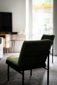 a green chair in a living room with a television at Das Quartier in Klagenfurt