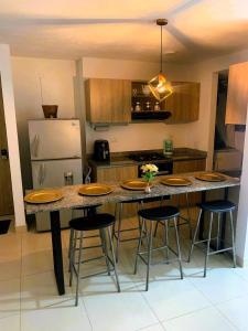 cocina con encimera grande con sillas y nevera en Encantador apartamento en pozos colorados, en Santa Marta