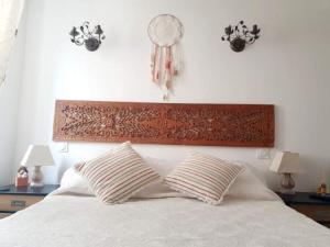 a white bed with two pillows and clocks on the wall at Petit duplex atypique in Furiani