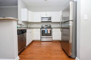 una cocina con armarios blancos y electrodomésticos de acero inoxidable en Comfortable Apartment with Pool Gym & other Amenities #2306, en Woburn
