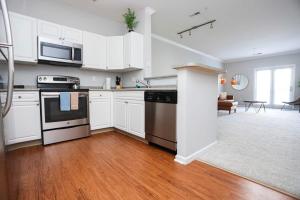 una cocina con armarios blancos y electrodomésticos de acero inoxidable en Comfortable Apartment with Pool Gym & other Amenities #3304, en Woburn