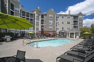 a large apartment building with a swimming pool and chairs at Comfortable Apartment with Pool Gym & other Amenities #4110 in Woburn