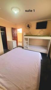 a bedroom with a white bed and a tv at Flamboyant hostel in Cabo Frio