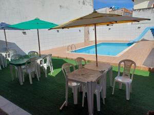 a table and chairs with umbrellas next to a pool at Flamboyant hostel in Cabo Frio