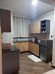 La cuisine est équipée d'armoires en bois et d'un réfrigérateur en acier inoxydable. dans l'établissement Buildnet 59 Najjera 1, à Kampala