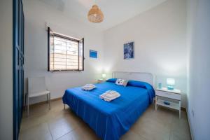 Schlafzimmer mit einem blauen Bett, einem Schreibtisch und einem Fenster in der Unterkunft A un passo dal Mare - Villa Corallo Torre Borraco in Manduria